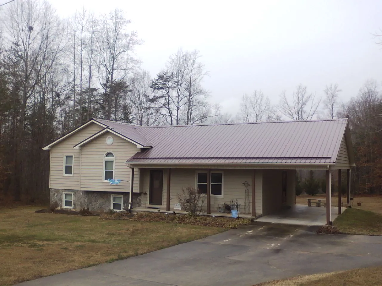 Burgundy metal roof on a tan split level home with an attached carport in Buchanan